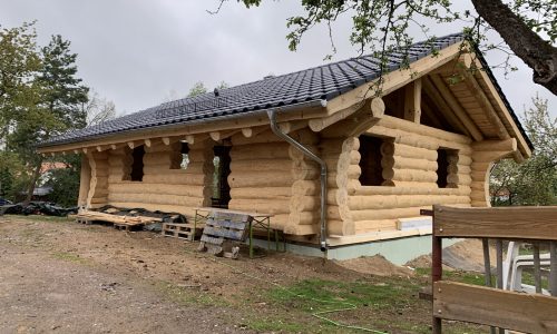 Rohbau eines Blockhauses mit sichtbarer Dachkonstruktion vor der Eindeckung.