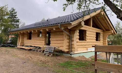 Rohbau eines Blockhauses mit sichtbarer Dachkonstruktion vor der Eindeckung.