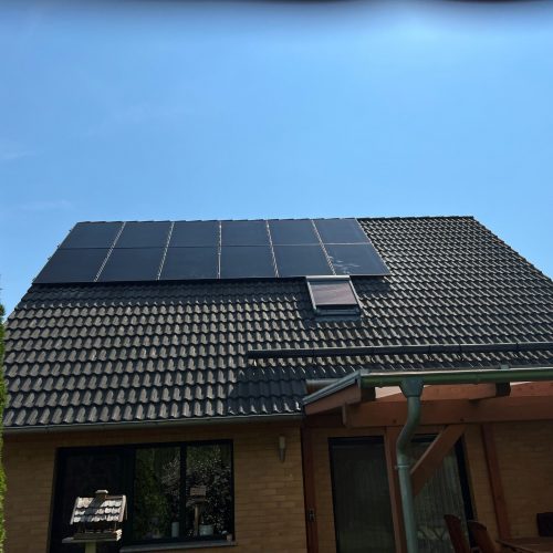 Detailaufnahme einer Photovoltaikanlage auf einem dunklen Dach.