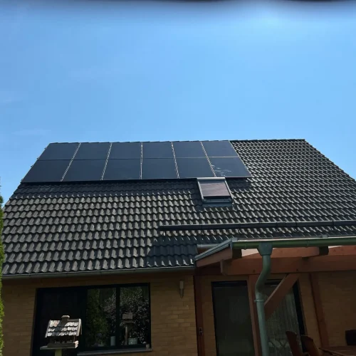 Detailaufnahme einer Photovoltaikanlage auf einem dunklen Dach.