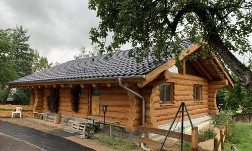 Neues Holzhaus mit frisch eingedecktem Ziegeldach nach Abschluss der Dacharbeiten.