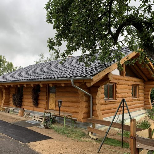 Neues Holzhaus mit frisch eingedecktem Ziegeldach nach Abschluss der Dacharbeiten.