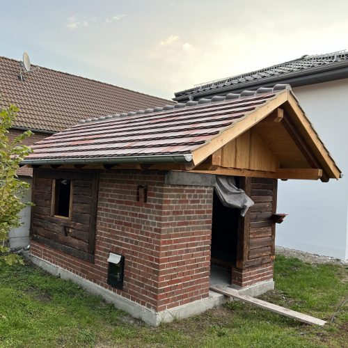 Dachsanierung an einem kleinen Backsteingebäude mit neuem Ziegeldach.