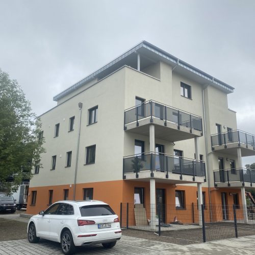 Mehrfamilienhaus mit Flachdach und moderner Fassade.