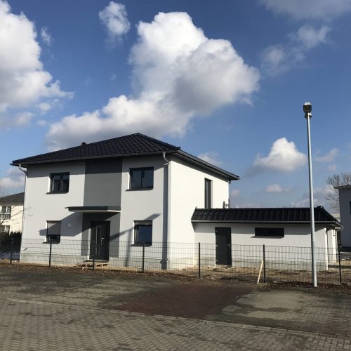 Neubau eines Einfamilienhauses mit abgeschlossenem Dach und Fassadenarbeiten.