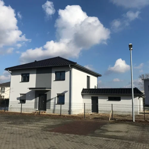 Neubau eines Einfamilienhauses mit abgeschlossenem Dach und Fassadenarbeiten.