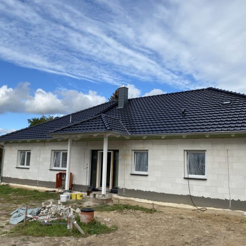 Weiß verputztes Haus mit kontrastreicher, dunkler Dacheindeckung.